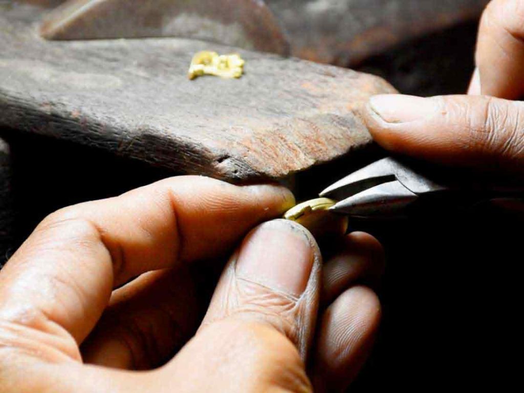 Close-up of a goldsmith filing a piece by hand at Bangkok Bespoke Jewelry
